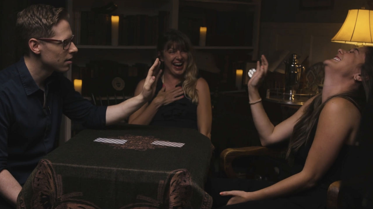 Two women laughing and smiling as magicain Ben Seidman performs The Oracle System mentalist trick for them