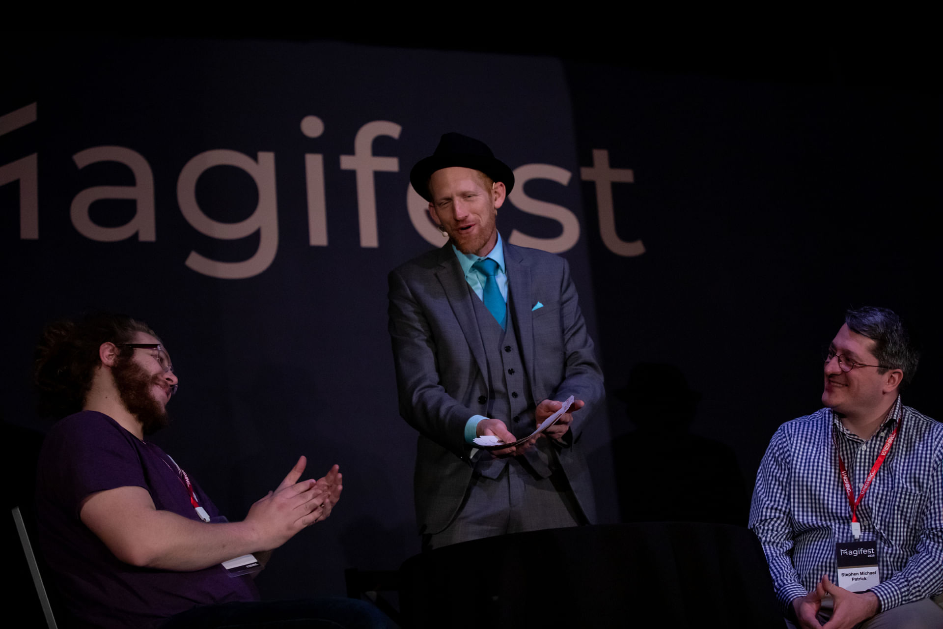 Magician in hat performs card trick on stage