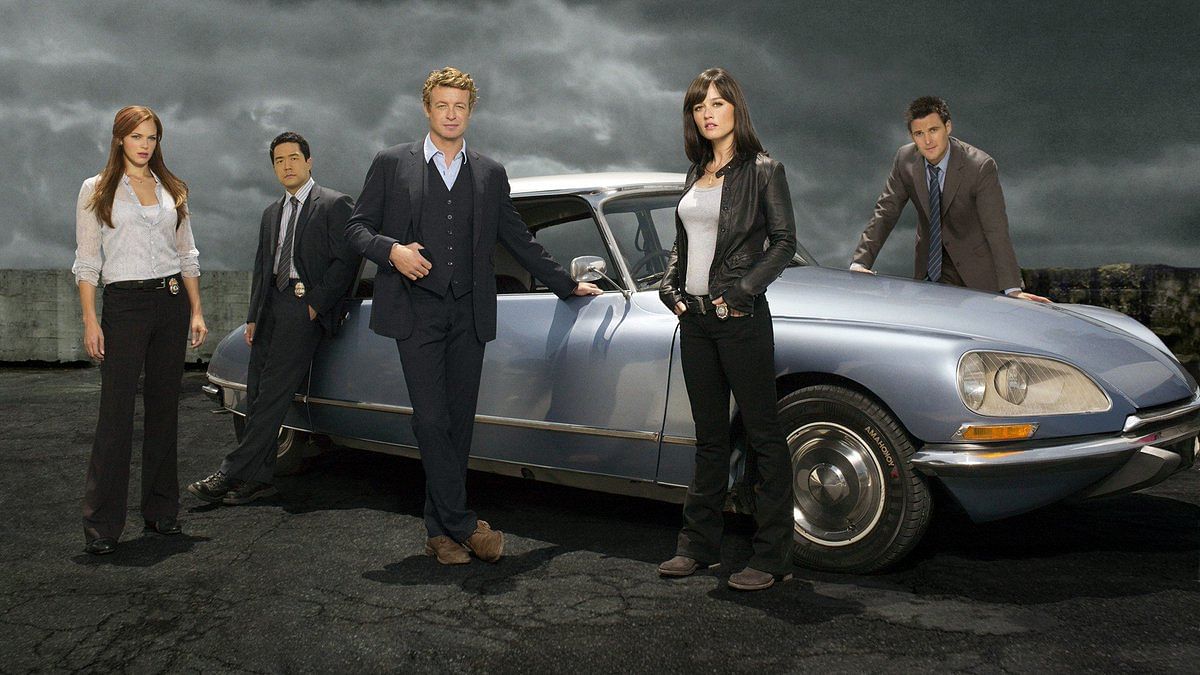The Mentalist cast poses in front of an antique car with Patrick Jane, who is played by Simon Baker, in front